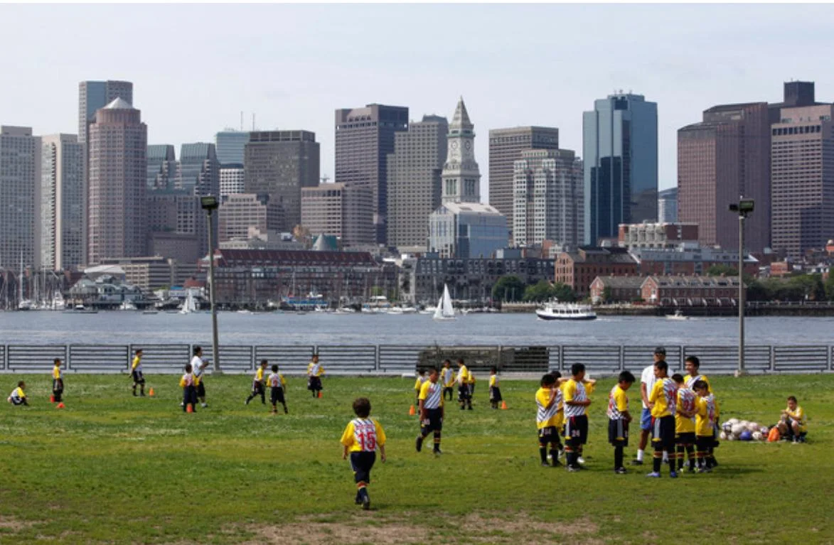 Niños futbolistas con ciudad de fondo jugando en cancha profesional